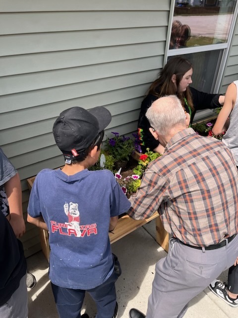 Students and senior citizens planting flowers